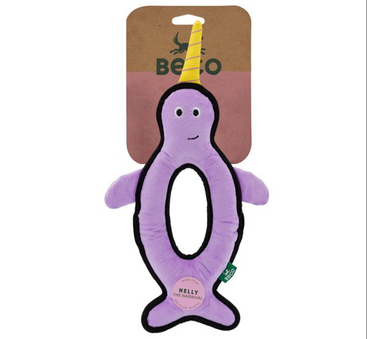 Purple narwhal-shaped toy with a yellow horn on a brown card, featuring the brand 'Beco'. Label states toy is called Nelly the Narwhal