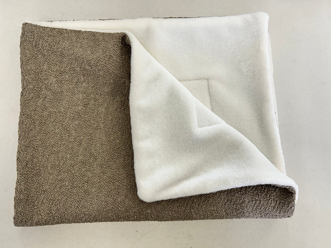 Brown bouclé blanket folded up with white inside 