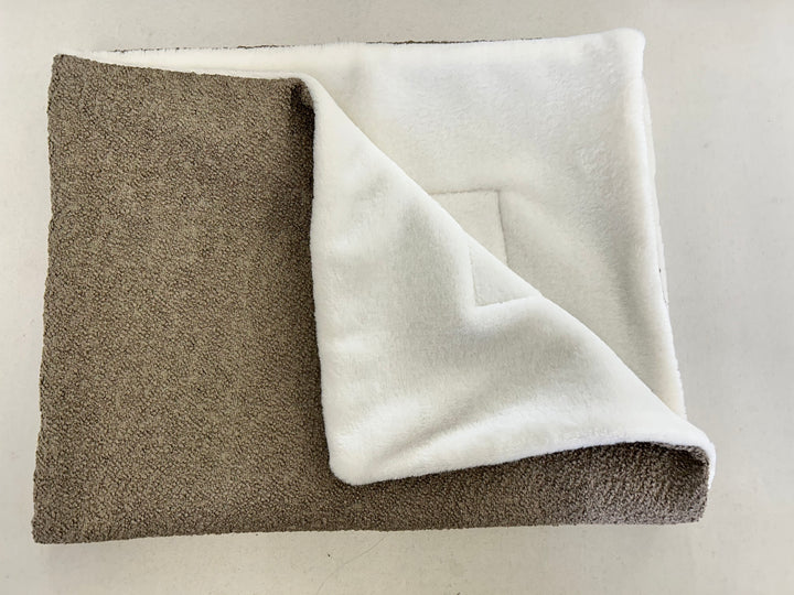Brown bouclé blanket folded up with white inside 