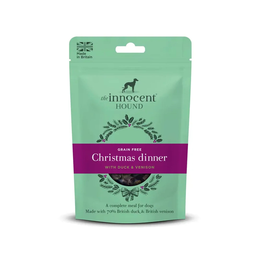 A stand-up pouch of The Innocent Hound dog food, specifically Christmas dinner (grain free, with duck & venison), in a mint green packaging with a purple band across the middle.