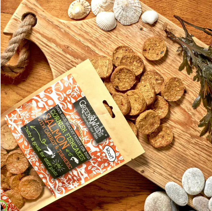 Image of Green & Wild's cornish fishcakes packaging staged on a chopping board with seashells, rocks and seaweed. 