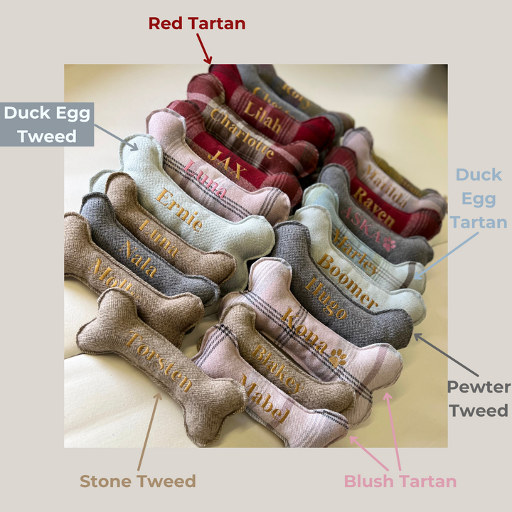 Various sizes of bone dog toys, with names embroidered on to them. Showing the fabric options of 'Red Tartan', 'Duck Egg Tartan', 'Duck Egg Tweed', 'Pewter Tweed', 'Blush Tartan' and 'Stone Tweed'