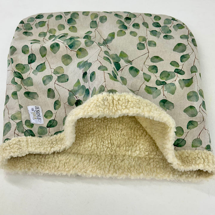 Snuggle sack with green leaf fabric outside and oat coloured faux sheepskin fabric inner