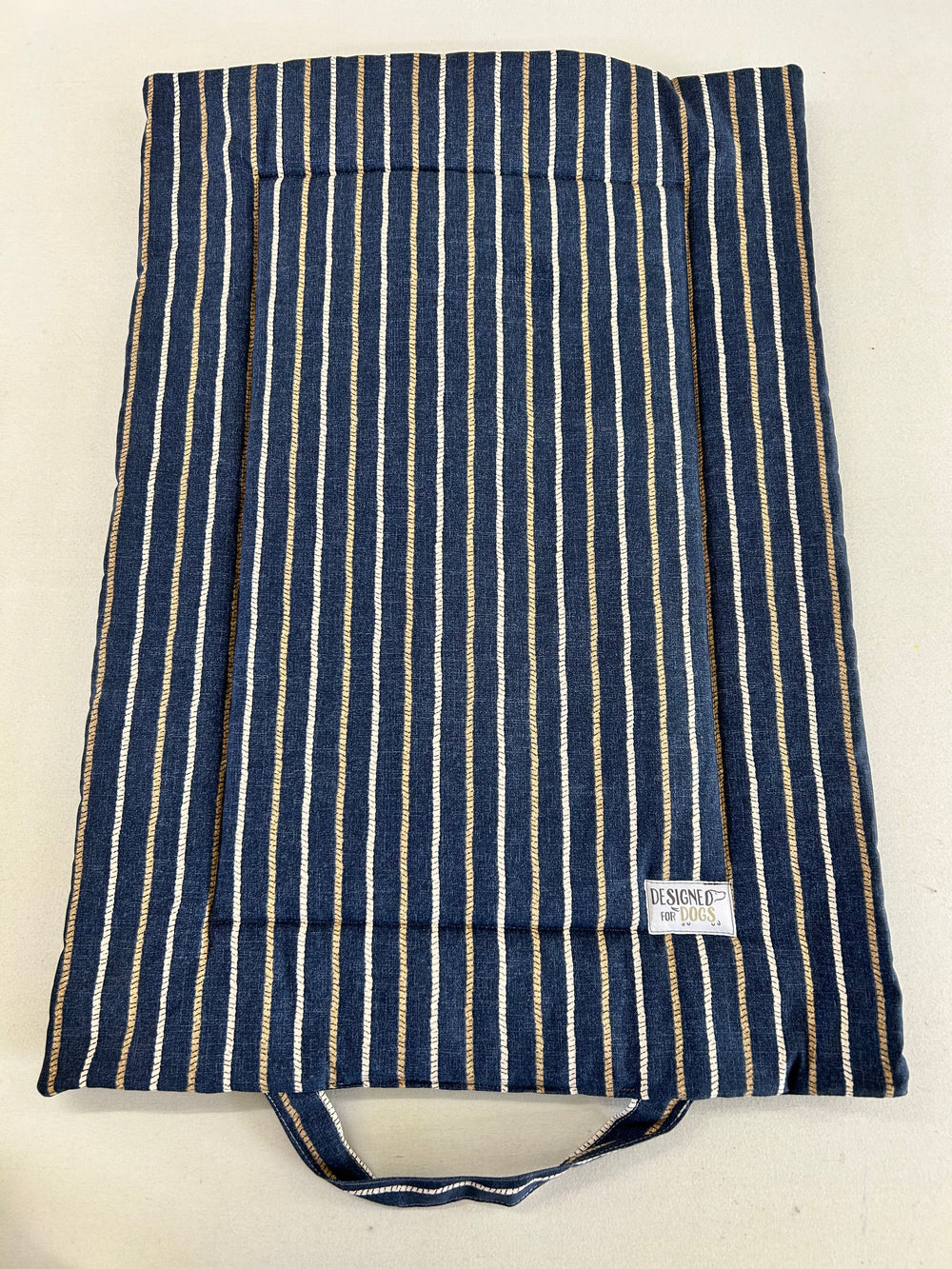 A fabric storage bag or organizer with vertical navy blue, white, and beige stripes, featuring a top handle and a small white brand label that reads 'KASUOJI'.