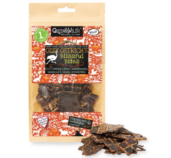 Green & Wild's Ozzy Ostrich's Blissful Bites dog treats in a clear windowed pouch with a beige outer sleeve and orange patterned label, shown with several dark brown treat pieces in front on a white background.