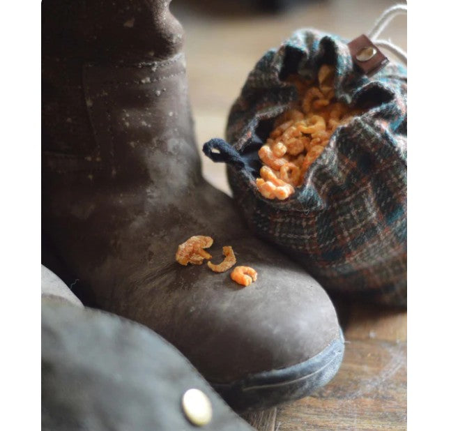 Skipper's prawn sprinkles in a fabric bag next to a pair of boots 