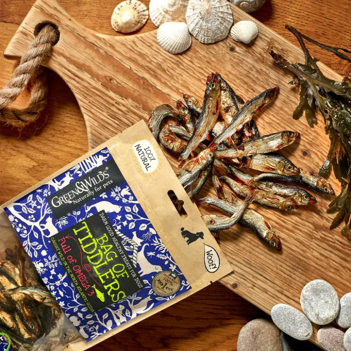 Green & Wild's Bag of Tiddlers packaging on a chopping board with seashells, seaweed and rocks in the background