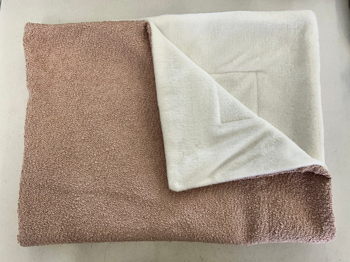 Pink bouclé fabric blanket with white inside, folded for the image 