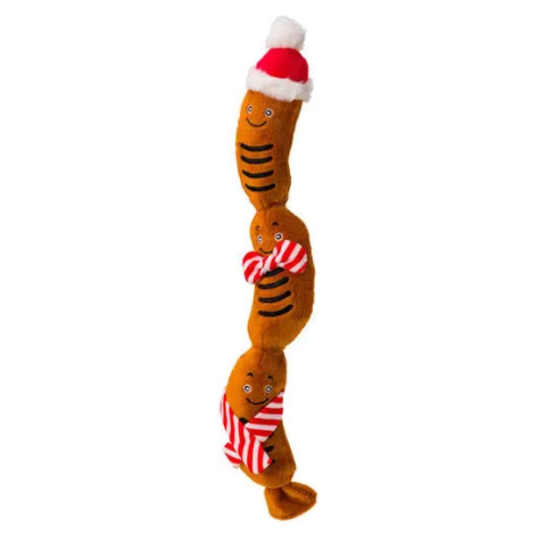 Plush dog toy with a sausage design wearing a Santa hat and striped scarf on a white background