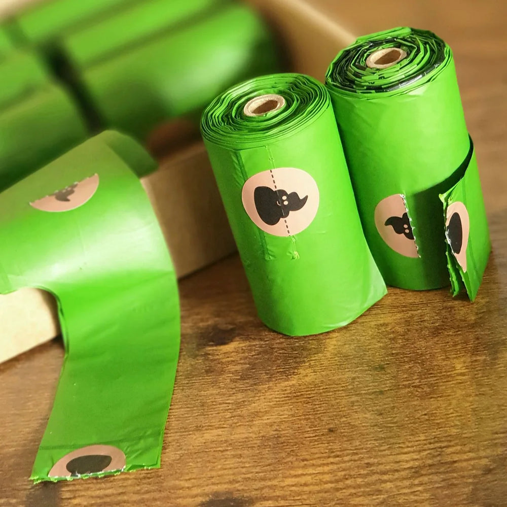 Rolls of green degradable eco-friendly dog poop bags with a cardboard core, designed to fit standard dispensers.