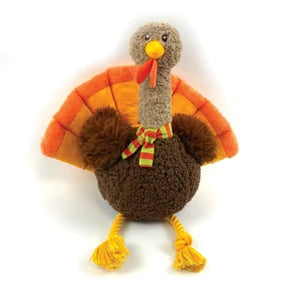 A plush turkey toy with a brown textured body, orange and yellow fan-shaped wings, a gray neck, yellow beak and legs, and a red wattle with a green and red striped bow, photographed on a white background.
