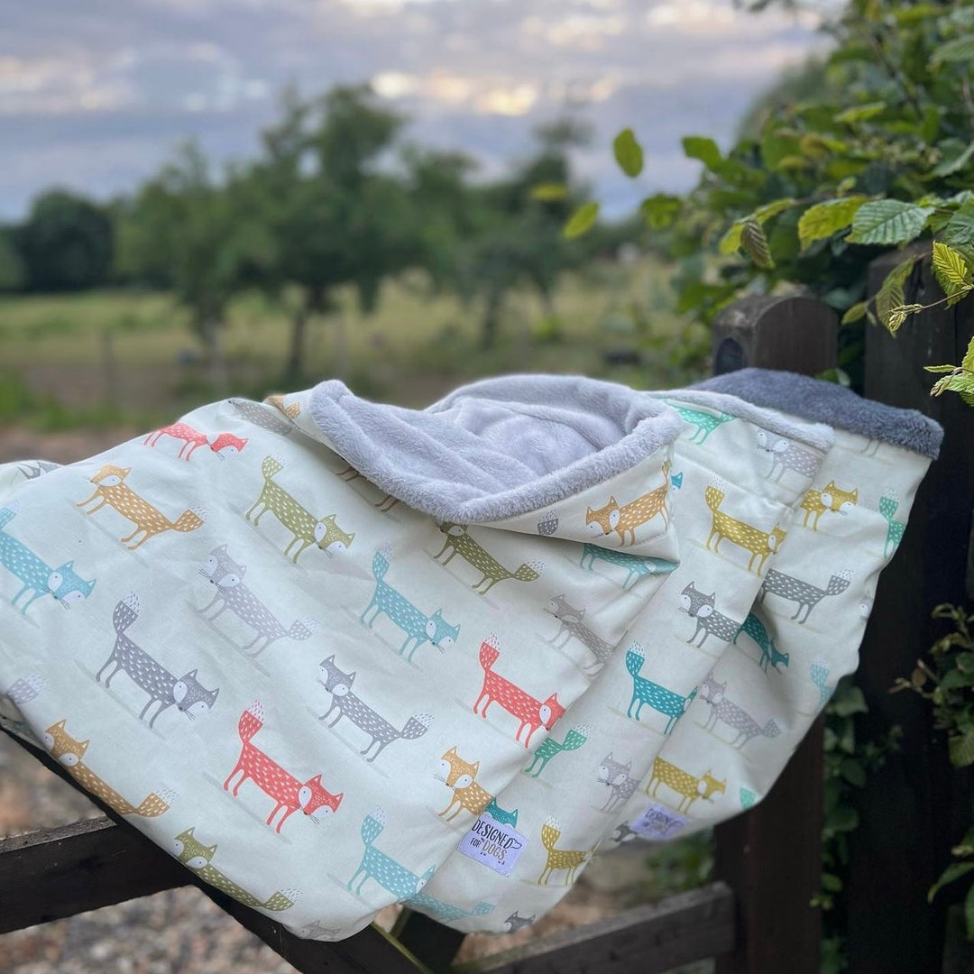Three snuggle sacks in teal colours with fox patterns. Shown on a gate